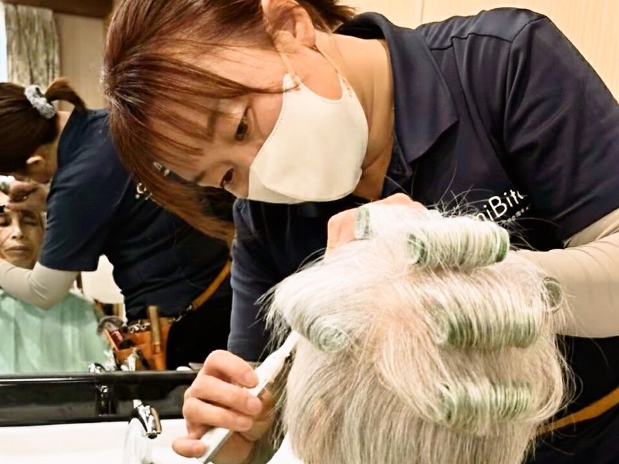 訪問先でパーマのロッドを巻く美容師
